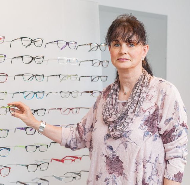 Optikerin vor der großen Auswahl an Brillengestellen